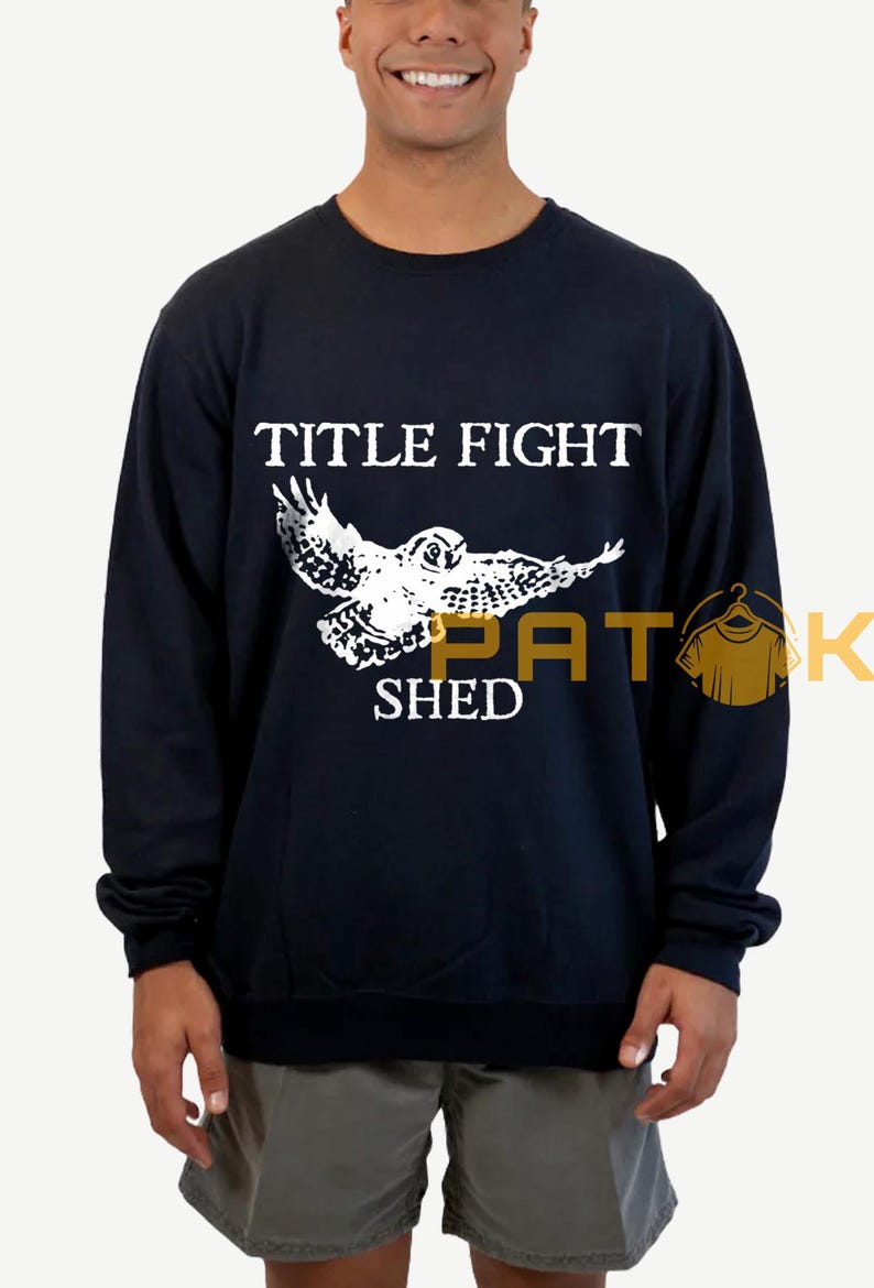 May include: Navy blue sweatshirt featuring a white owl graphic and the text "TITLE FIGHT SHED". The owl is shown with its wings spread. The sweatshirt is a long-sleeved crew neck.