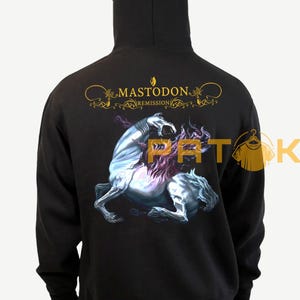 May include: Black hoodie featuring the band name "Mastodon" and album title "Remission" in gold lettering. The back displays a detailed illustration of a mythical creature. The hoodie has a hood and long sleeves.