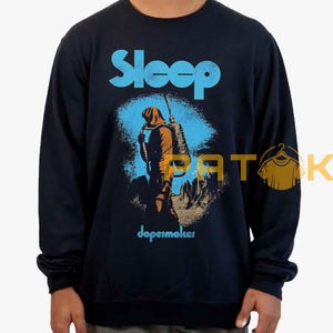 Pu&ograve; includere: Felpa blu navy con la scritta "Sleep" in azzurro. La grafica raffigura una figura con zaino e bastone, con la parola "dopesmoker" sotto.