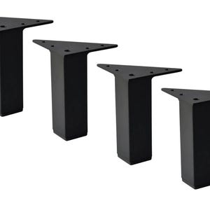 May include: Four black metal furniture legs. Each leg has a triangular top with pre-drilled holes for mounting and a rectangular base. The legs are designed for furniture such as tables, chairs, or sofas.