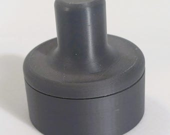May include: A dark gray, cylindrical coffee tamper with a flat base and a ridged handle. The handle is cylindrical and slightly wider at the top. The tamper is designed for pressing coffee grounds in a portafilter.