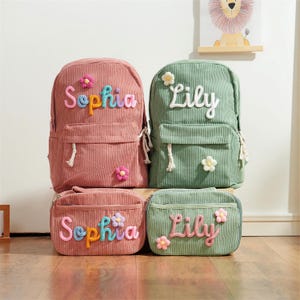 May include: Four corduroy backpacks and matching pouches in pink and green. The backpacks and pouches are personalized with the names "Sophia" and "Lily" in colorful, embroidered letters. Each bag is decorated with flower accents.