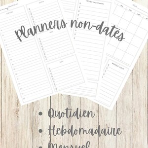May include: A stack of undated white planners with gray text on a light wood grain background. The planners include daily, weekly, and monthly layouts. Text on the planners includes "Planners non-dates", "Quotidien", "Hebdomadaire", and "Mensuel".