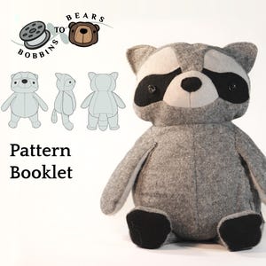 May include: A handmade gray raccoon plush toy with black accents around the eyes and on the paws. The image also includes a pattern booklet with illustrations and the text "Pattern Booklet". The logo "Bears to Bobbins" is also visible.