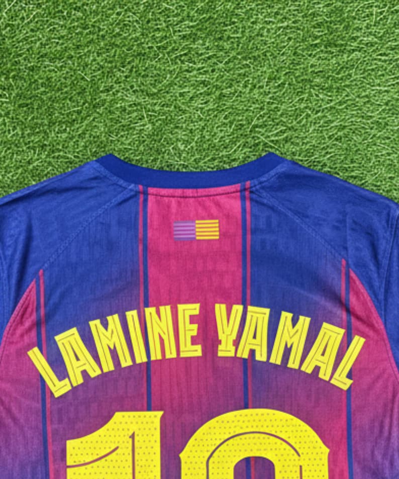May include: A blue and maroon soccer jersey with the name "LAMINE YAMAL" in yellow lettering across the back. The number "10" is also visible in yellow. The jersey has a striped design and a small emblem.