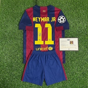 Pode incluir: Um conjunto de camisa e calção de futebol Neymar Jr. em azul e bordô. A camisa apresenta o número 11 em amarelo, o nome Neymar Jr. e o logotipo da UNICEF. Um certificado de autenticidade está incluído.