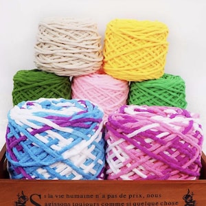 Puede incluir: Una caja de madera llena de madejas de hilo de colores. El hilo es de varios colores, incluyendo crema, amarillo, verde, rosa, azul, morado y rosa. El hilo está dispuesto en una exhibición visualmente atractiva, perfecto para proyectos de manualidades. La caja tiene texto en francés.