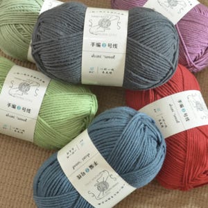 May include: A collection of colorful yarn skeins in shades of green, gray, blue, red, and purple. Each skein has a white label with Chinese text and the words "shuxi wool". The yarn is tightly wound, suggesting it's suitable for knitting or crochet projects.