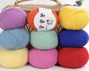 May include: A collection of colorful yarn balls in shades of purple, blue, yellow, orange, green, pink, and red. The yarn balls are stacked in front of a wicker basket. One ball has a white label with Chinese text.