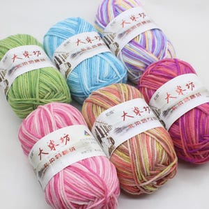 May include: A selection of multi-coloured yarn skeins in shades of green, blue, pink, purple, and orange. Each skein has a white label with Chinese characters. The yarn looks soft and is suitable for knitting or crochet projects.