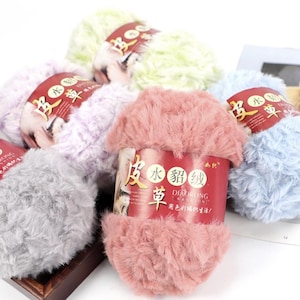 Puede incluir: Una colección de ovillos de lana esponjosa en varios colores pastel, incluyendo rosa, lavanda, verde claro y azul. Cada ovillo está envuelto con una etiqueta con caracteres chinos. La lana tiene un aspecto suave y texturizado, adecuada para proyectos de punto o ganchillo.