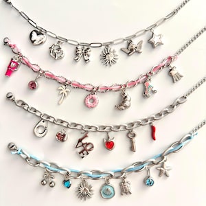 Peut inclure: Quatre bracelets à breloques argentés ornés de divers pendentifs, notamment un cœur, un nœud, un soleil, une étoile, un palmier, un donut, un patin à roulettes, des menottes, un piment rouge, une clé, des cerises, une tortue et une étoile de mer.