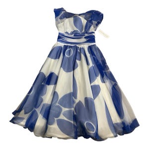 May include: A sleeveless knee-length dress featuring a white base with a large blue floral pattern. The garment has a gathered, fitted waistline and a full, flared skirt made of a sheer, layered fabric. A small white clothing tag is attached.