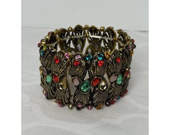 Brazalete elástico grueso con diamantes de imitación dorados de colores y diseño original.
