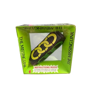 May include: A black rectangular puzzle box titled THE MISSING LINK with yellow and green chain link graphics. The packaging features bright green borders, text reading INSTRUCTIONS INSIDE, and information about ordering the solution.