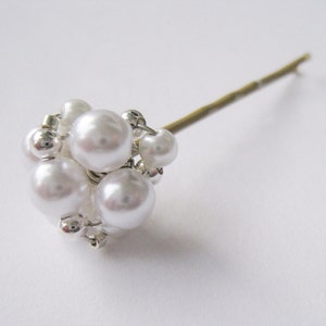 May include: A white pearl hair pin with a cluster of pearls attached to the end of a gold wire.