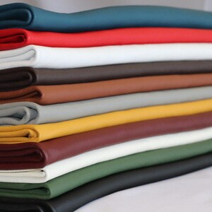May include: A collection of folded leather fabric in a range of colours. The colours include teal, red, white, brown, tan, grey, yellow, burgundy, green, and black. The leather has a smooth appearance and a slight sheen.
