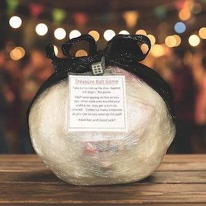 May include: A wrapped ball game with a black bow and a die on top. The game is wrapped in clear plastic and has a tag that reads "Treasure Ball Game". The game instructions are printed on the tag.