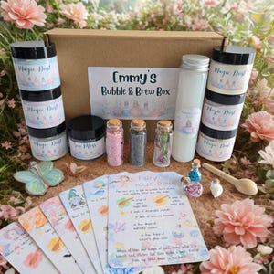 May include: A selection of fairy-themed items, such as glitter, sea moss, and magic dust in jars, a potion bottle, and recipe cards. The box is labelled "Emmy's Bubble & Brew Box."