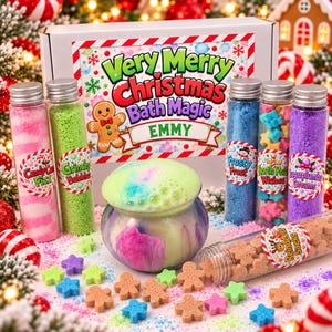 May include: A Christmas-themed bath product set featuring a white box labeled Very Merry Christmas Bath Magic EMMY, five glass tubes filled with colorful bath salts, and a small cauldron containing bubbling green and pink bath foam.
