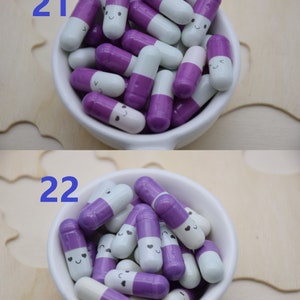 Puede incluir: Un cuenco de cer&aacute;mica blanco lleno de cuentas con forma de c&aacute;psula morada y blanca, cada una con una cara sonriente. El n&uacute;mero "21" est&aacute; en la esquina superior izquierda de la imagen superior, y el n&uacute;mero "22" est&aacute; en la esquina superior izquierda de la imagen inferior. El fondo es una superficie de madera clara.