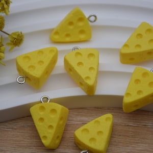 Peut inclure: Six breloques en forme de fromage jaune avec des anneaux de saut argentés. Les breloques en fromage sont en forme de triangles avec des trous.