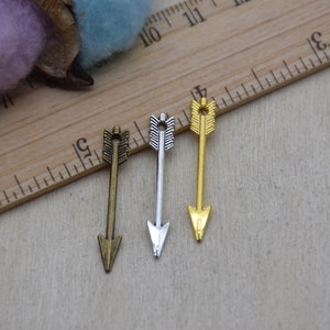 May include: Three arrow charms in different finishes: gold, silver, and bronze. The arrows are all the same size and shape, with a simple design.
