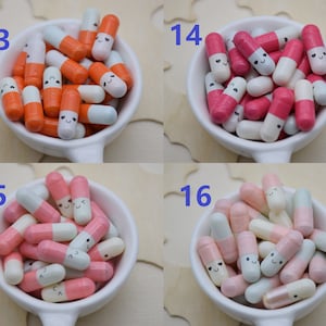 Puede incluir: Una colecci&oacute;n de objetos coloridos en forma de c&aacute;psula sonriente en peque&ntilde;os cuencos blancos. Las c&aacute;psulas est&aacute;n en varias combinaciones de colores, incluyendo naranja y blanco, rosa y blanco, y rosa claro y azul. Las c&aacute;psulas tienen peque&ntilde;as caras sonrientes.