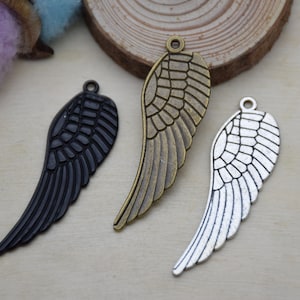 May include: Three metal angel wing charms in different finishes: black, bronze, and silver. Each charm has a loop at the top for attaching to jewellery or other crafts.
