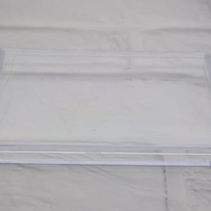 May include: A clear plastic square box with a smooth surface.
