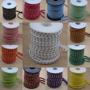 May include: Assortment of spools of suede cord with gold studs. The cords are in various colors, including black, pink, white, brown, green, yellow, and purple.