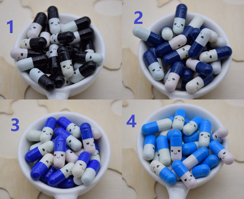Puede incluir: Una colecci&oacute;n de cuentas decorativas en forma de c&aacute;psula en un cuenco blanco. Las cuentas est&aacute;n en cuatro combinaciones de colores: negro y blanco, azul marino y blanco, azul y blanco y azul claro y blanco. Cada cuenta tiene una cara sonriente.
