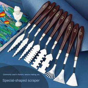 Pode incluir: Um conjunto de nove espátulas de formato especial com cabos castanhos e lâminas prateadas. As lâminas têm várias formas, incluindo desenhos serrilhados e em forma de leque. O texto "Special-shaped scraper" é visível.