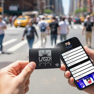 May include: A black card with the Laser Studio USA logo and a Wi-Fi symbol is held in front of a smartphone displaying a user interface. The background shows a busy city street with pedestrians and yellow taxis.