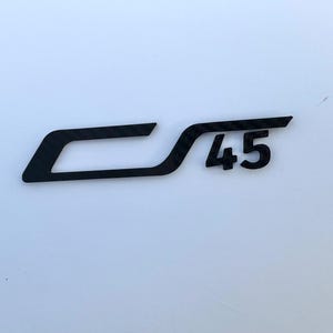 May include: Black emblem with the text "CS 45" on a white background. The emblem has a stylized design with the letters "CS" connected and the number "45" to the right.
