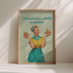 Könnte beinhalten: Ein gerahmter Druck mit einem Retro-Bild einer Frau, die zwei Schokoladen-Chip-Cookies hält. Sie trägt eine gelbe Bluse, eine türkisfarbene Schürze und ein Stirnband. Der Text auf dem Druck lautet: "Eine ausgewogene Ernährung ist ein Keks in jeder Hand."