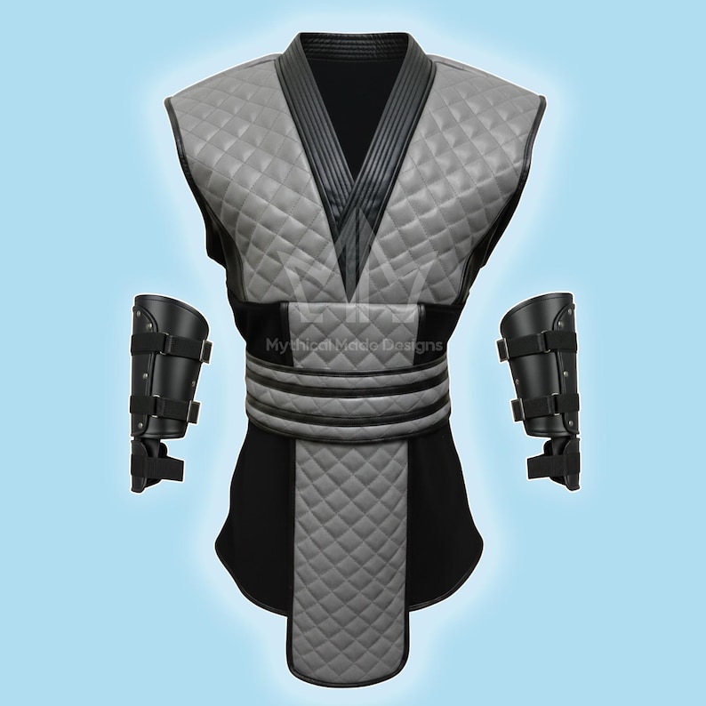 May include: A gray and black quilted costume with matching arm guards. The costume features a V-neck design and a quilted pattern on the chest and lower portion. The arm guards are black with adjustable straps. The text "Mythical Made Designs" is visible.