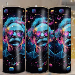 May include: A black tumbler featuring a vibrant, colorful illustration of Albert Einstein wearing sunglasses. The design includes a cosmic background with planets and the equation E=mc². The tumbler has a silver straw.