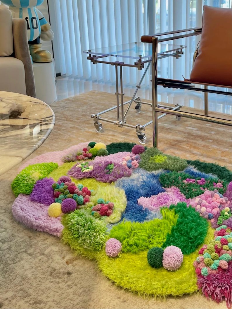 Peut inclure: Un tapis abstrait color&eacute; avec une vari&eacute;t&eacute; de textures et de couleurs. Le tapis pr&eacute;sente un m&eacute;lange de teintes vertes, bleues, violettes et roses, avec un aspect duveteux et textur&eacute;. Le design comprend des pompons et des sections touffues, cr&eacute;ant un rev&ecirc;tement de sol artistique unique.