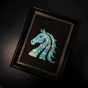 Puede incluir: Obra de arte enmarcada con la silueta de una cabeza de caballo. El caballo está hecho de mosaicos iridiscentes en tonos azules, verdes y amarillos. La obra está sobre un fondo negro dentro de un marco negro con ribete dorado.
