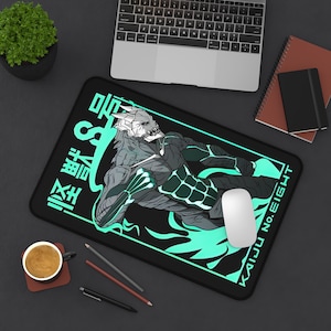 May include: Black rectangular mousepad featuring a monster illustration in shades of gray and teal. The text "KAIJU NO. EIGHT" and Japanese characters are displayed in teal. A white mouse and laptop are also visible.