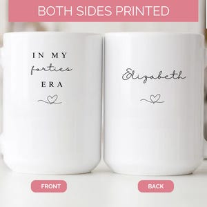 May include: Two white ceramic mugs, each with a handle, are displayed. One mug reads "IN MY forties ERA" with a heart symbol. The other mug has the name "Elizabeth" and a heart. The text "BOTH SIDES PRINTED" is at the top.