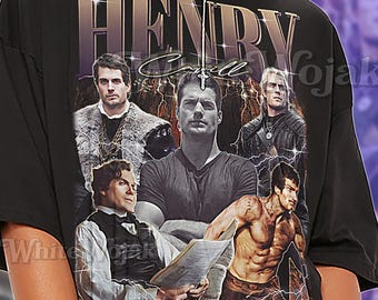 May include: Black unisex t-shirt featuring a graphic of Henry Cavill in various roles. The shirt has the text "HENRY Cavill" in a stylized font. The word "Unisex" is printed below the graphic. The shirt is oversized.