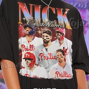 May include: Black unisex t-shirt featuring a graphic of baseball players with the text "NICK Castellanos" and "Phillies". The shirt has the text "SHIRT Unisex" at the bottom.