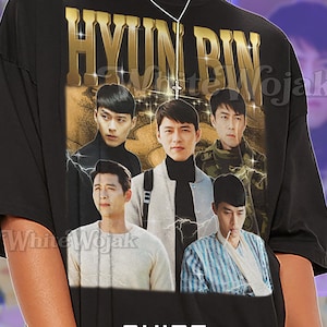 Puede incluir: Camiseta unisex negra con un gráfico dorado con el nombre "HYUN BIN" y las imágenes de un hombre. La camiseta también tiene el texto "SHIRT Unisex".