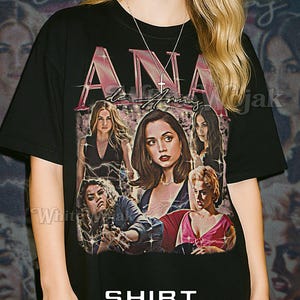 May include: Black unisex t-shirt featuring a graphic of several women with the text "ANA" in pink. The shirt also has the words "Shirt Unisex" in white. The model is wearing a 2XL shirt.