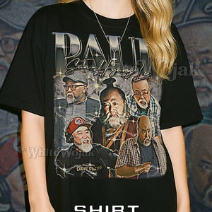 May include: Black unisex t-shirt featuring a graphic of several men with the text "DAX Sun-st-jung Lee". The shirt also has the text "DAVE FILONI" and "SHIRT Unisex". The model is wearing a 2XL shirt.