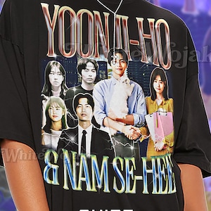 May include: Black unisex t-shirt featuring a graphic of several people with the text "YOON-HO" and "& NAM SE-HE". The shirt also has the word "Unisex" and the text "SHIRT".