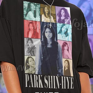 Könnte beinhalten: Schwarzes Unisex-T-Shirt mit einer Collage von Bildern und dem Namen "PARK SHIN-HYE" in Weiß. Das Shirt hat das Wort "SHIRT" über "Unisex" in einer stilvollen Schriftart. Das Shirt ist aus einem weichen Material.