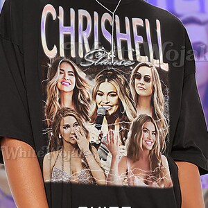 May include: Black unisex t-shirt featuring a graphic of several women with the text "CHRISHELL Stause". The shirt also includes the text "SHIRT Unisex".